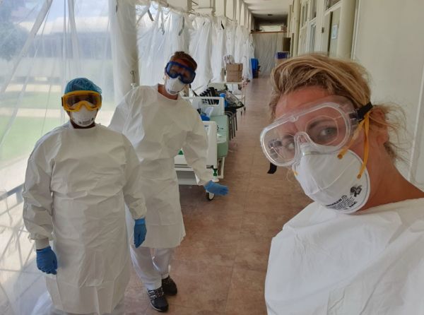 foto van Ilse met twee collega's, helemaal ingepakt in beschermingsmiddelen, in de gang van een medisch centrum