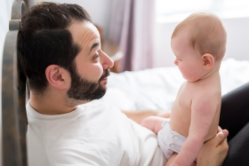 vader trekt gek gezicht naar baby op schoot